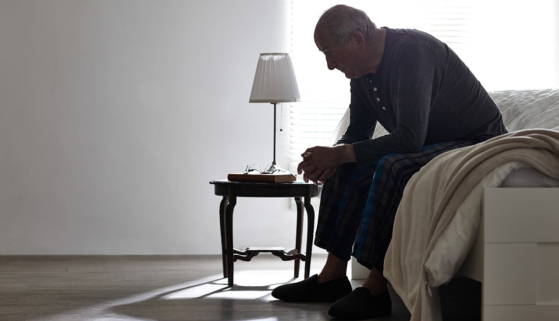 sad man sitting on edge of bed