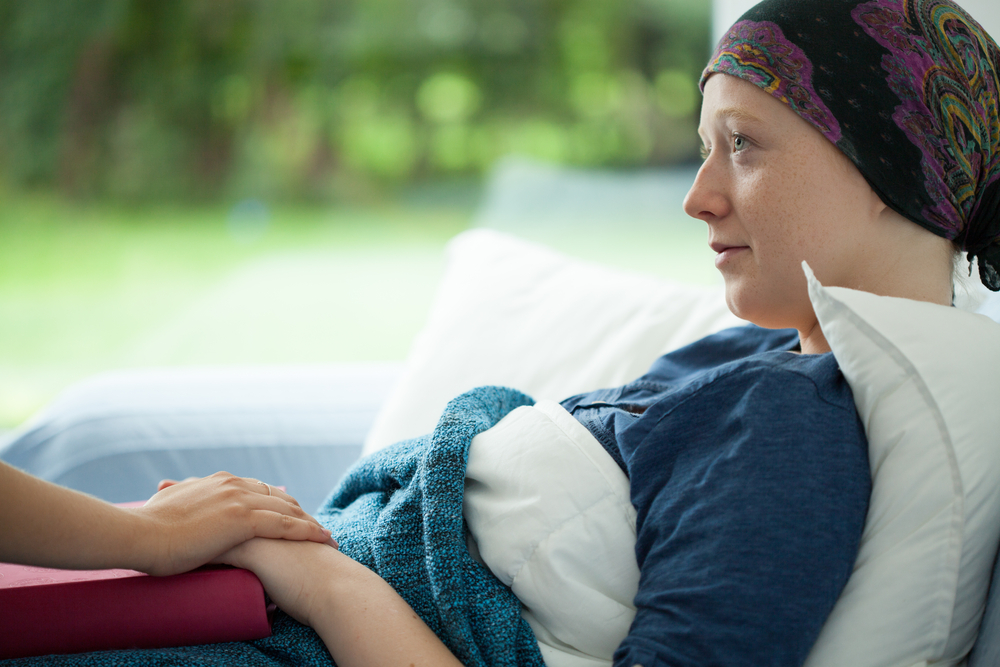 Cancer woman lying in bed supported by mum