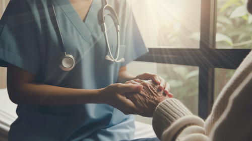 Clinician holding hands with a senior with rays of sunlight streaming in
