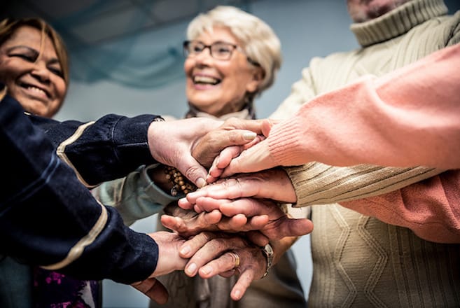 Grief Support Group - group of women with stacked hands in a circle